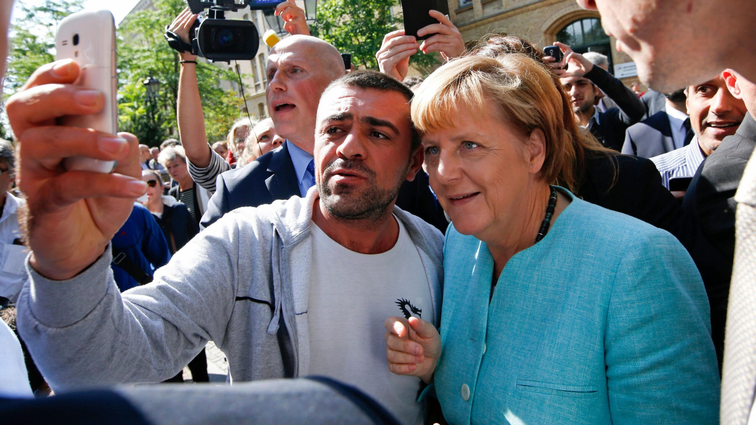 Angela Merkel taking a selfie with a Syrian refugee