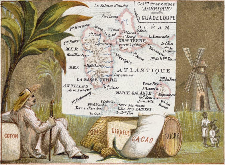 A man in white suit, broad-rimmed hat and what looks like a cane lounges against a bag of cotton beneath tropical trees while two people with dark skin work in a field. A map of the island is also on the card.