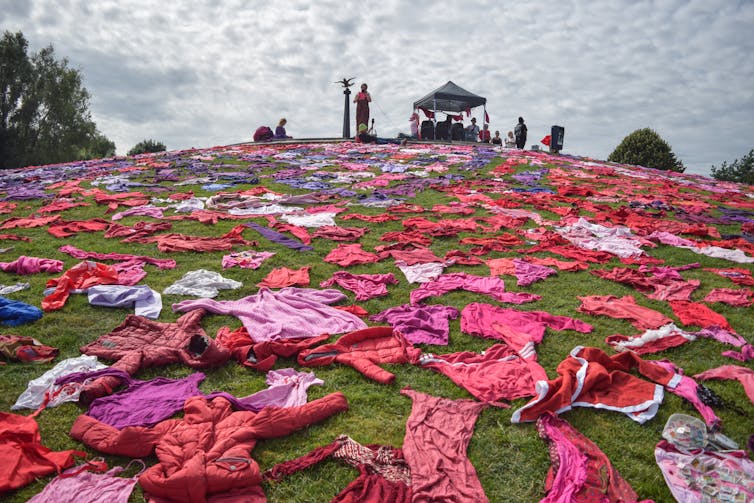 Dyed clothing are scattered over a hillside in reds and blues.