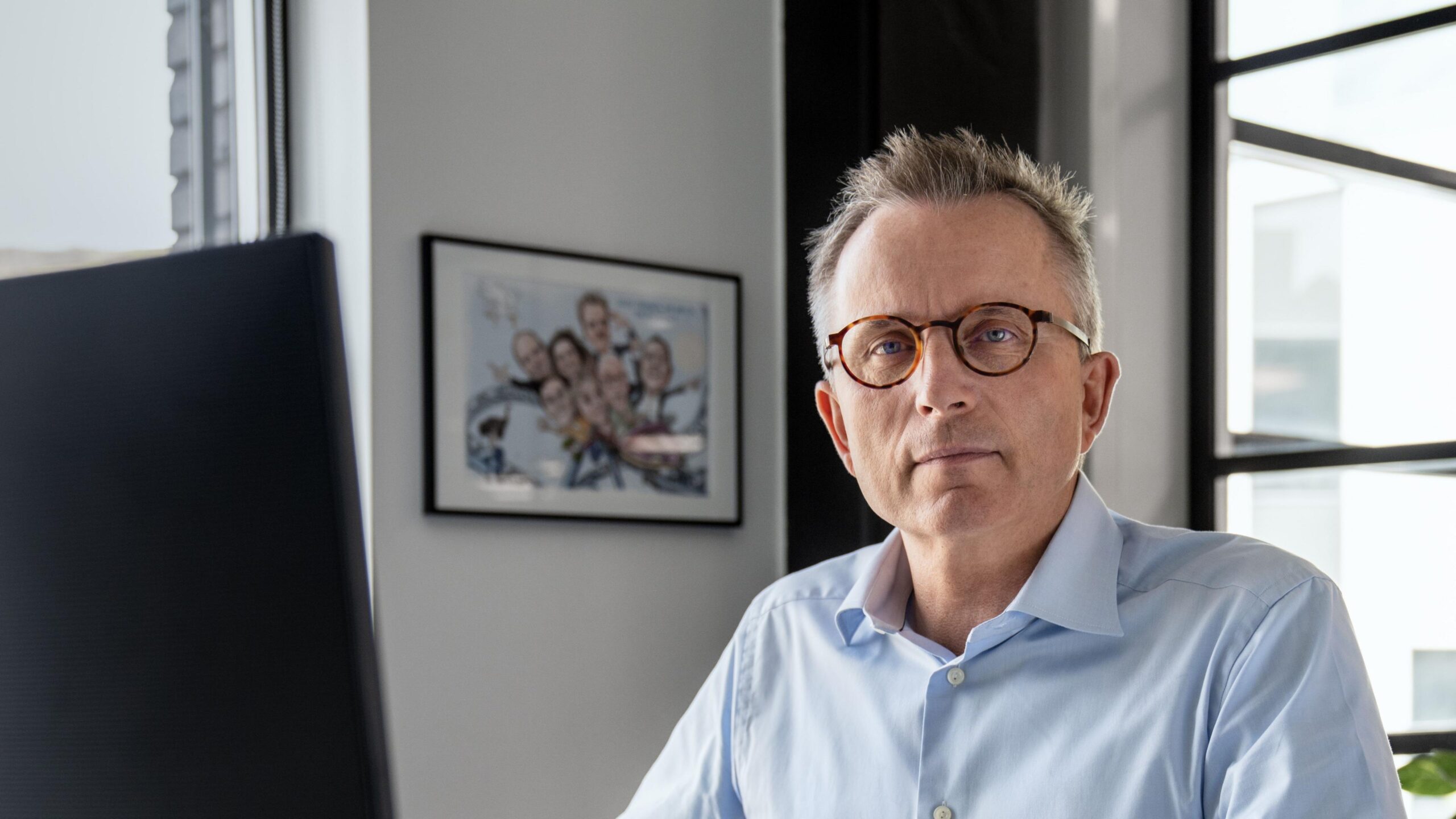 Hermann Haraldsson wearing round glasses sits at his desk
