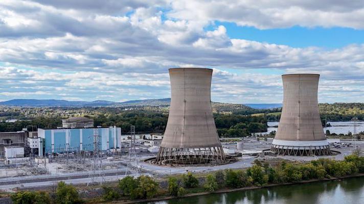 Two huge cooling towers stand Three Mile Island, to the left is blue and white power station.