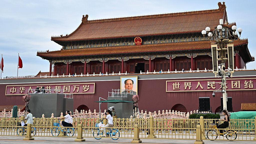 People ride past a portrait of the late communist leader Mao Zedong on Tiananmen Square on 28 August. 