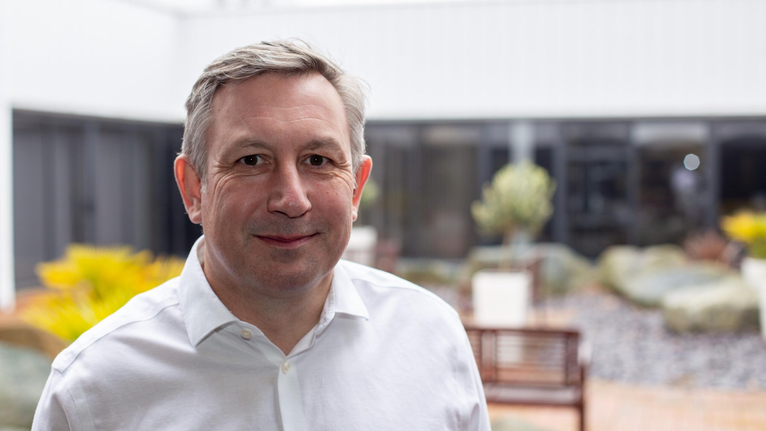 Wearing a smart, white shirt, Nick Rutter smiles at the camera.