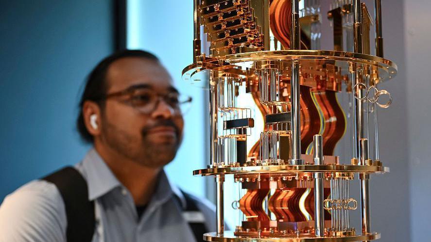 A bystander looks at the gold electronics of an IBM quantum computer