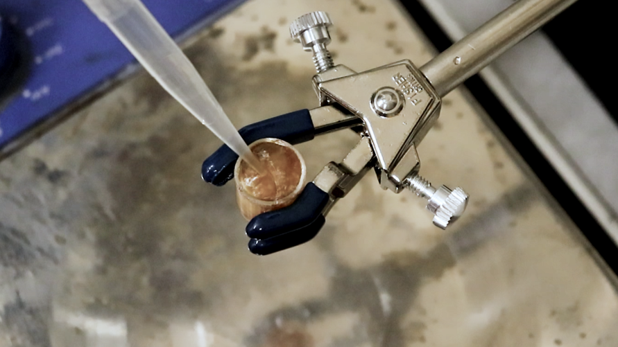 A pipette is held close to a test tube containing a brown gel. It's part of a molecular solar thermal energy storage experiment at the University of California, Santa Barbara.